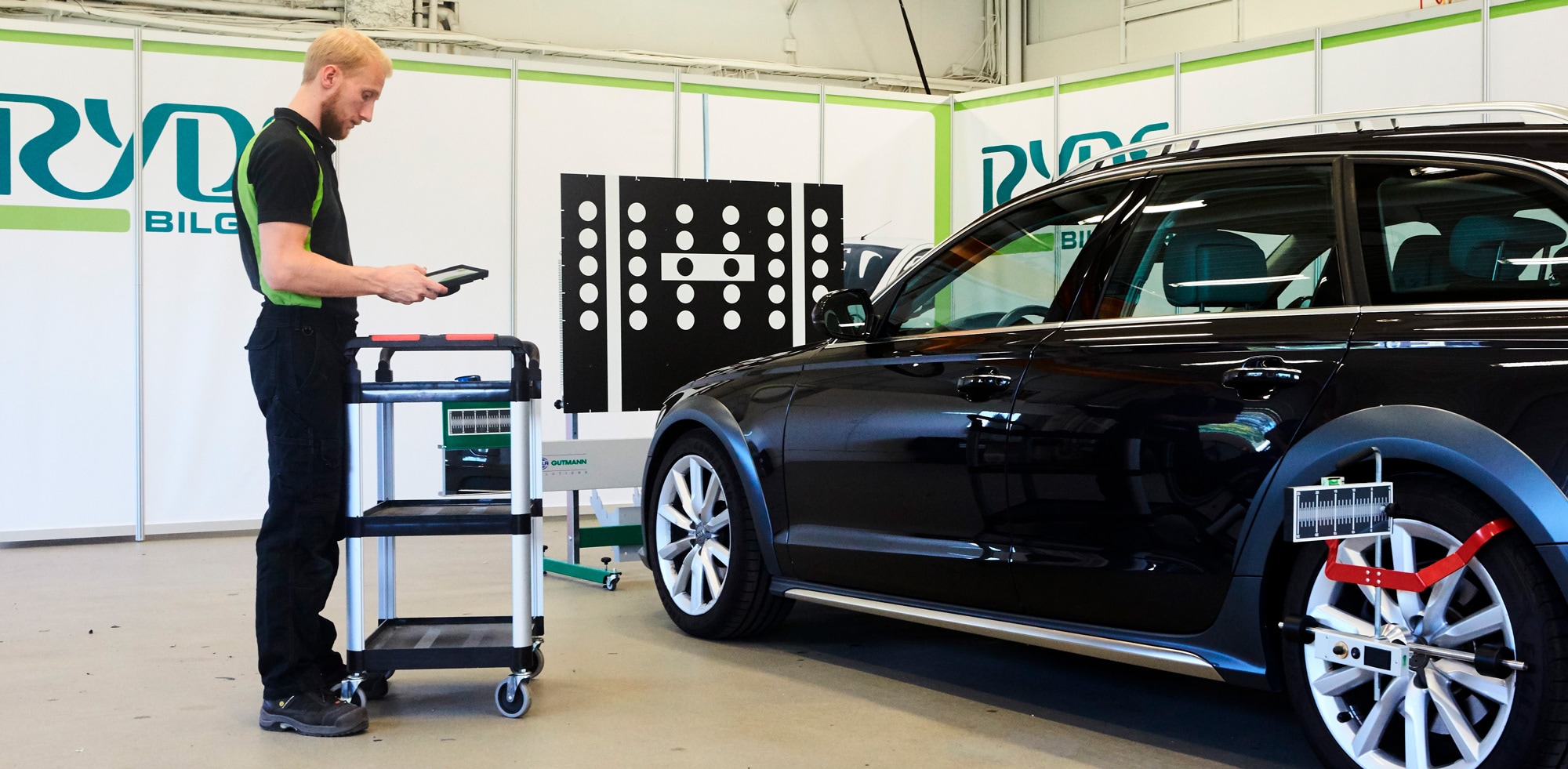 Rydsbilglas anställd man står och kalibrerar en bil med en läsplatta
