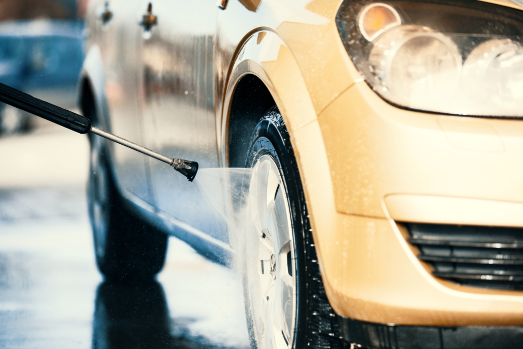 Gul bil som får fälgen tvättat av en högtrycks spruta